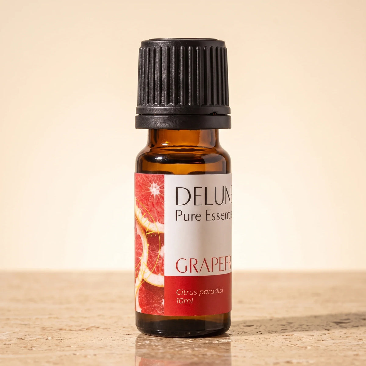 Delune Grapefruit (Pink) Pure Essential Oil, 10ml amber glass bottle on warm travertine stone