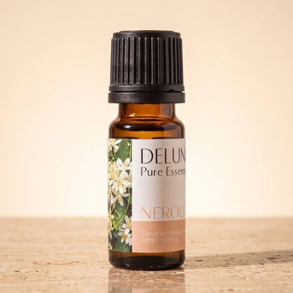 Delune Neroli Pure Essential Oil, 10ml amber glass bottle on warm travertine stone