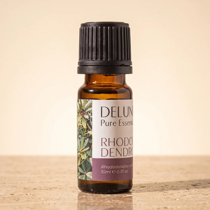 Delune Rhododendron Leaf Pure Essential Oil, 10ml amber glass bottle on warm travertine stone